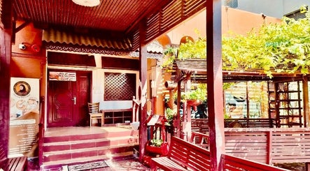 Charming entrance of Thai Rose Massage Center in Ajman, AE, surrounded by lush greenery and inviting decor.