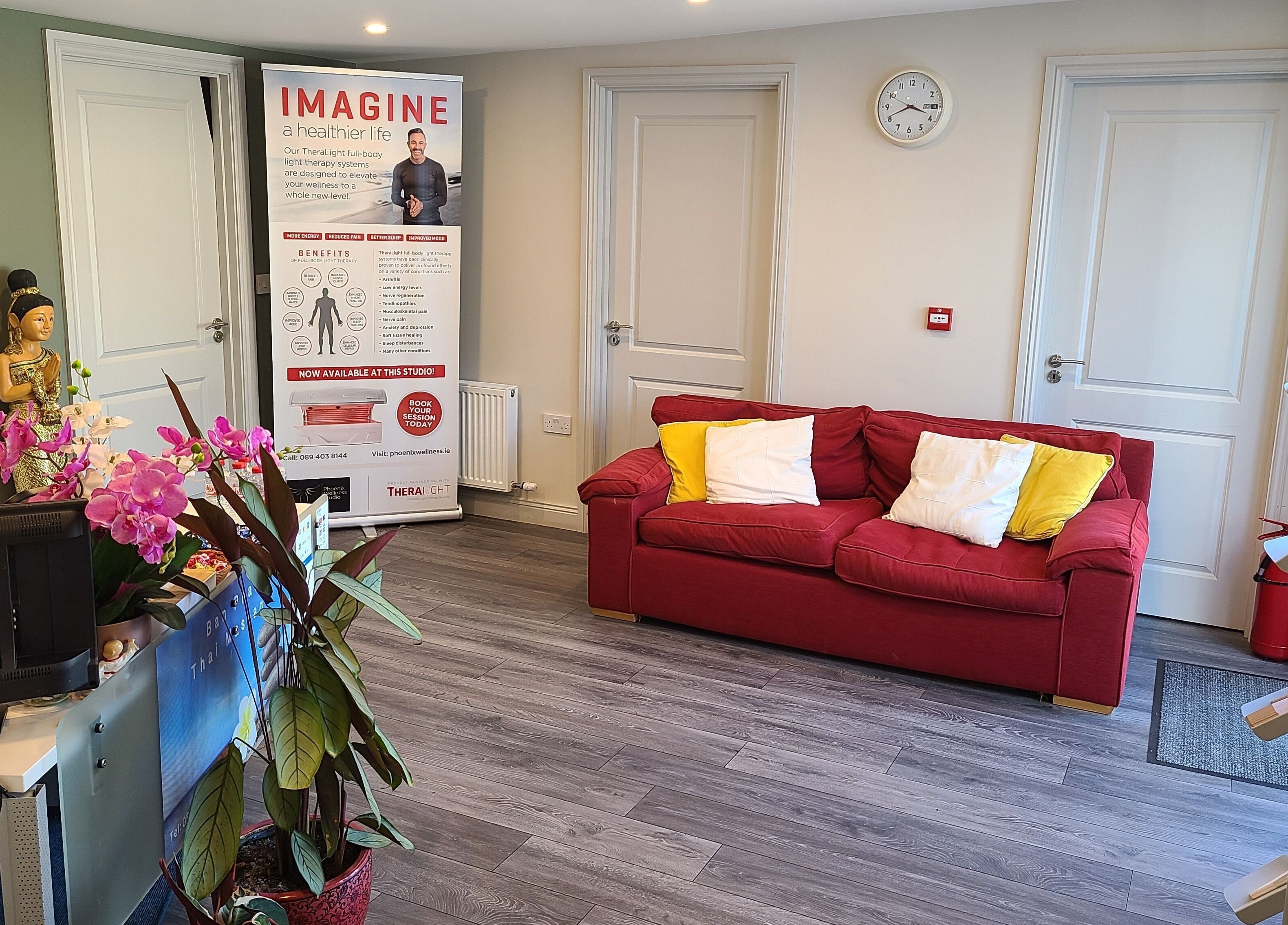 Reception area at Phoenix Wellness, Gorey, Ireland with a red sofa, vibrant decor, and welcoming atmosphere.