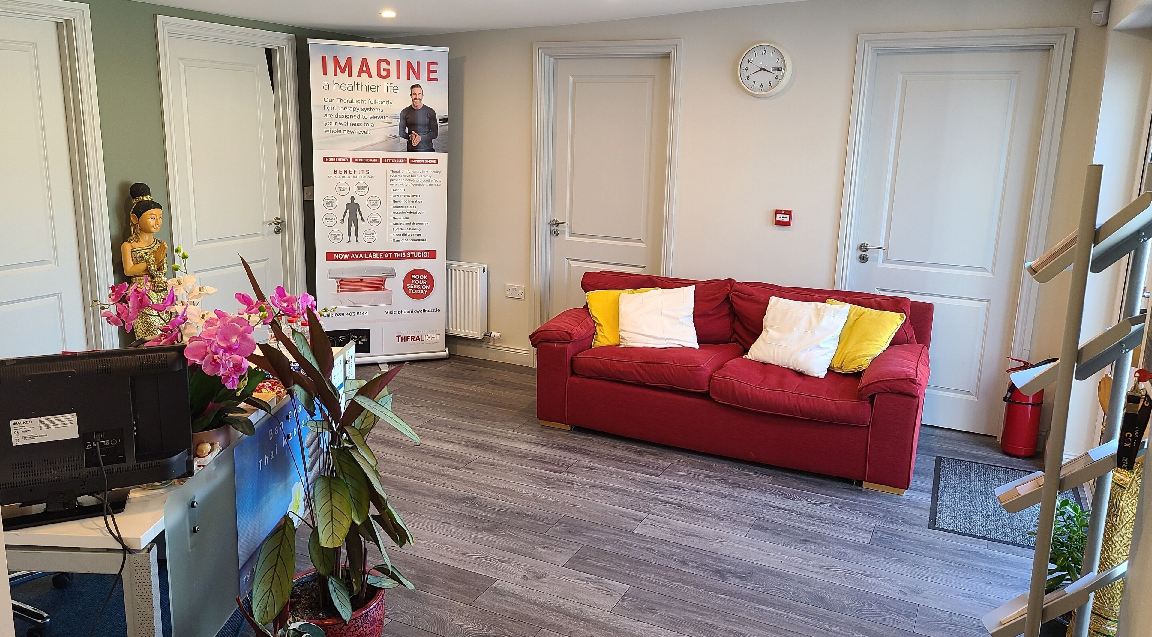 Reception area at Phoenix Wellness, Gorey, Ireland with a red sofa, vibrant decor, and welcoming atmosphere.