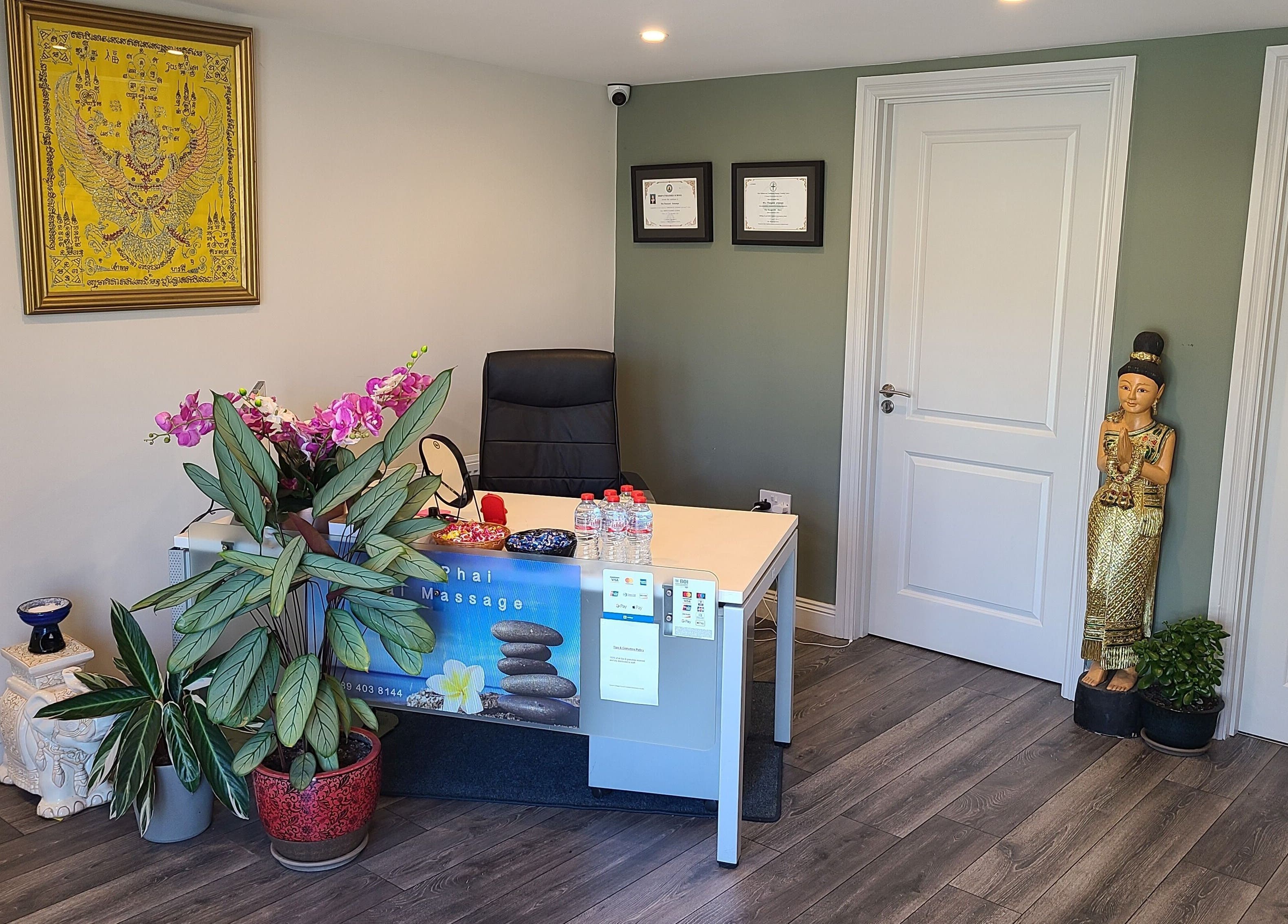 Reception desk with plants at Phoenix Wellness, Gorey, Ireland, IE, featuring Thai decor and certificates.