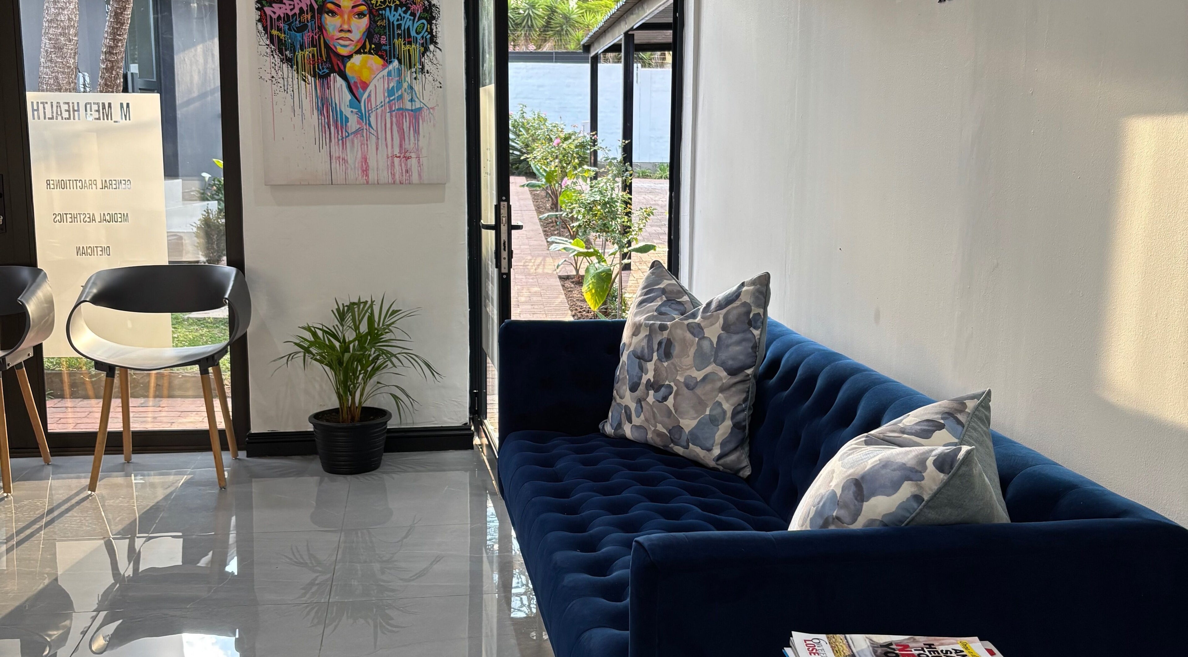 Cozy lounge area in Meela Aesthetics, Randburg, Gauteng, ZA, featuring a navy sofa and artful decor.