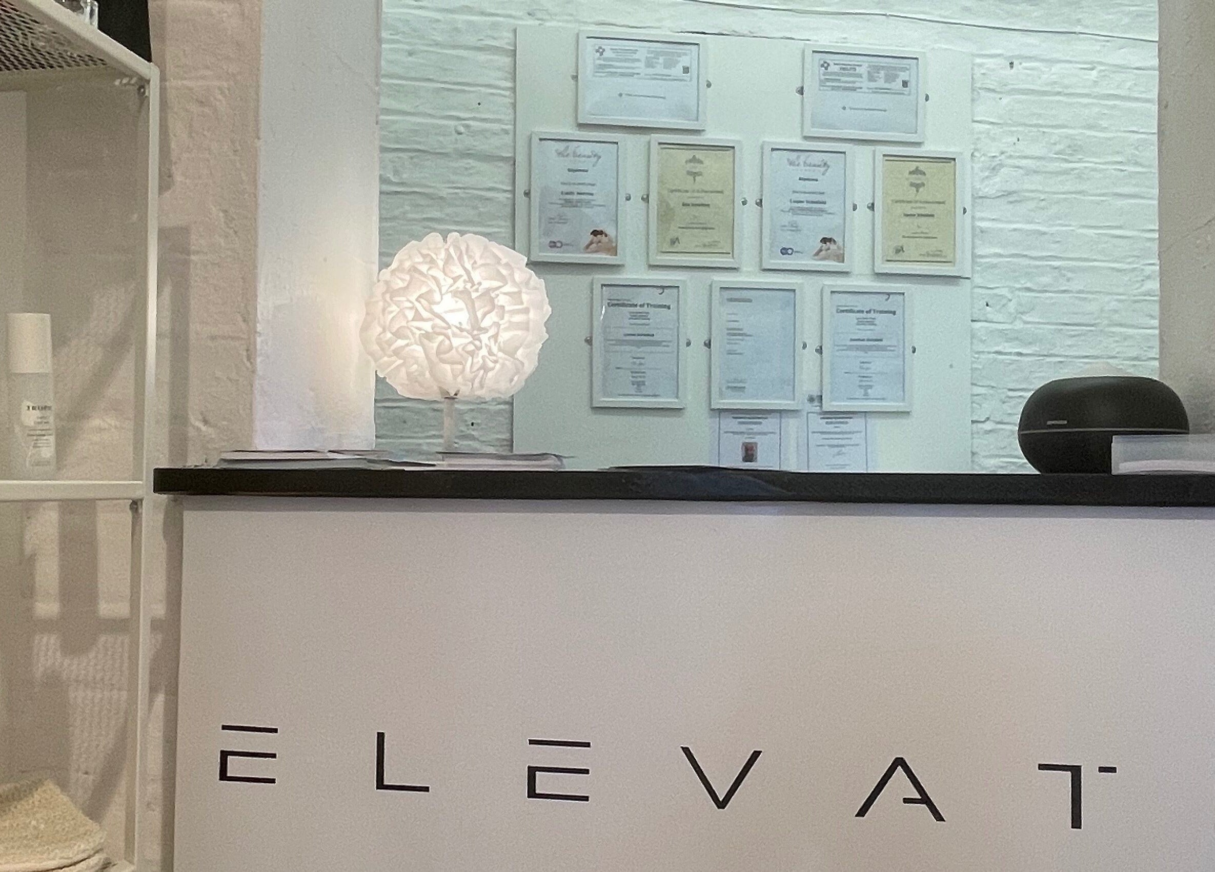 Reception desk at Elevate in Ripon, England, GB, featuring glowing lamp and displayed beauty products.
