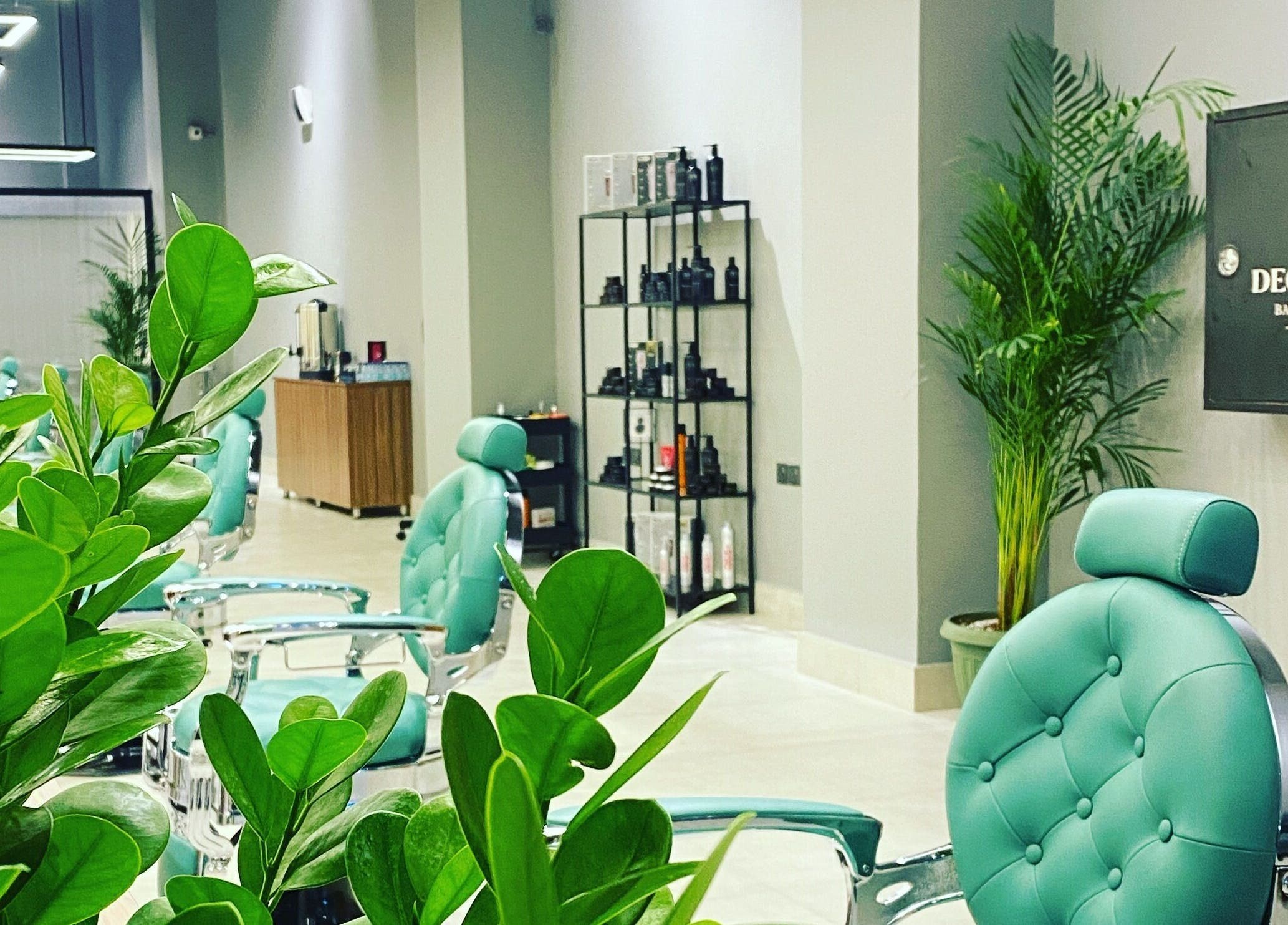 Bright interior of Degrees Barbershop in Riyadh, SA, showcasing stylish chairs and lush greenery.