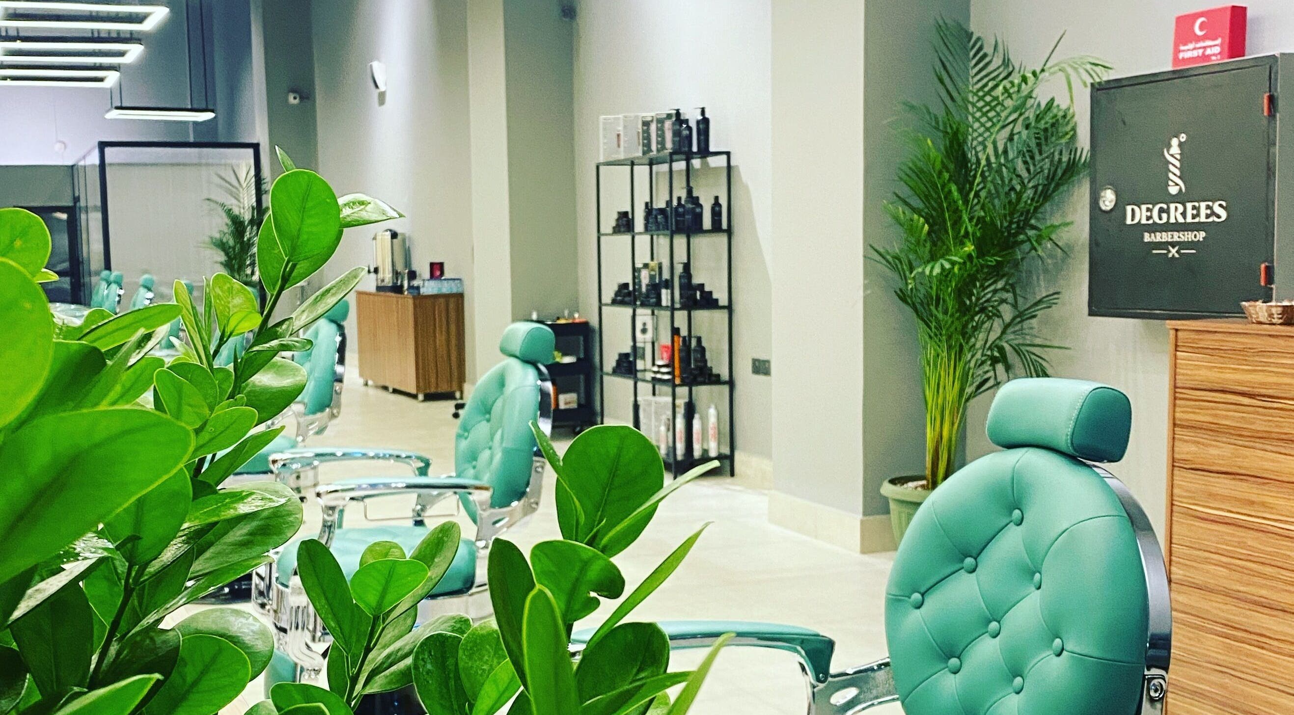Bright interior of Degrees Barbershop in Riyadh, SA, showcasing stylish chairs and lush greenery.