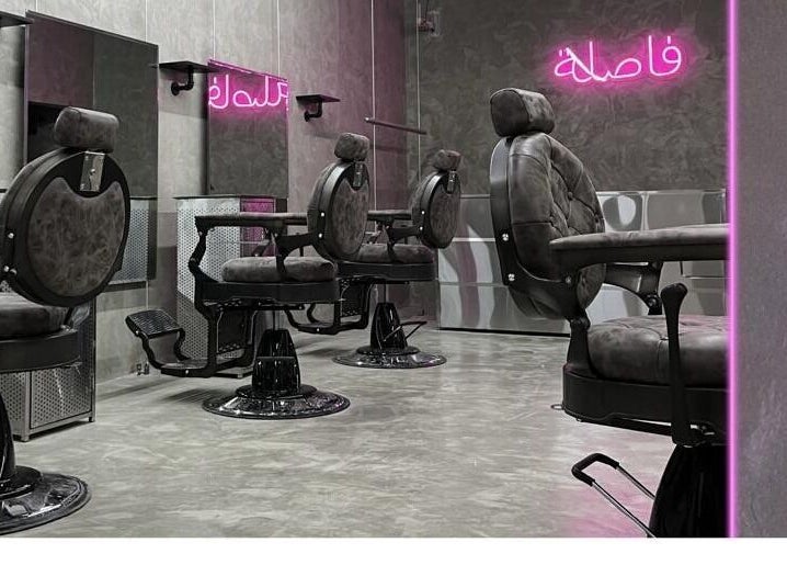 Chic interior of Comma Barber in Riyadh, Riyadh Province, SA, featuring stylish barber chairs and glowing neon lights.