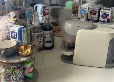Beverage station at Maison de Maya, Basildon, England, GB with coffee maker, syrups, and cups.