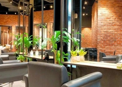 Chic salon interior at C.Michael London in Kuala Lumpur, featuring modern black chairs and lush plants.