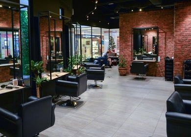 Modern salon interior at C.Michael London, Kuala Lumpur, with sleek black chairs and brick walls.