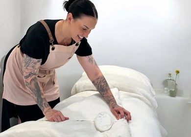 Therapist at Exhale Holistic Skin in Bentleigh East, Victoria, AU preparing a treatment bed.