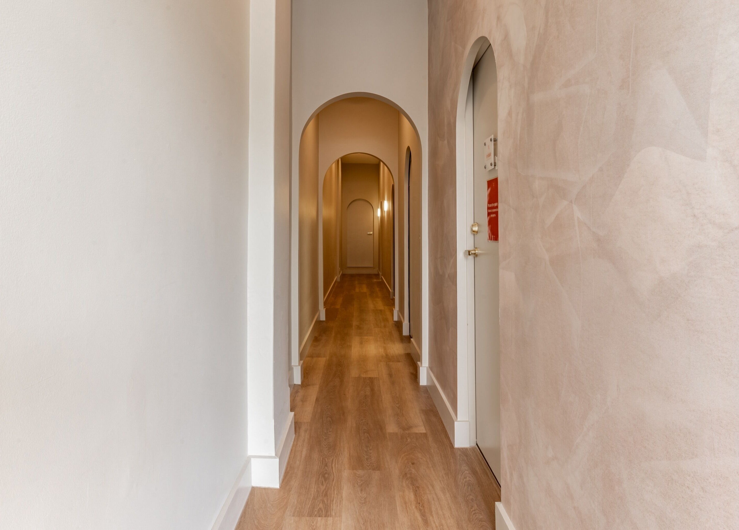 Serene hallway at Exhale Holistic Skin in Bentleigh East, Victoria, AU, featuring elegant arches and wood flooring.