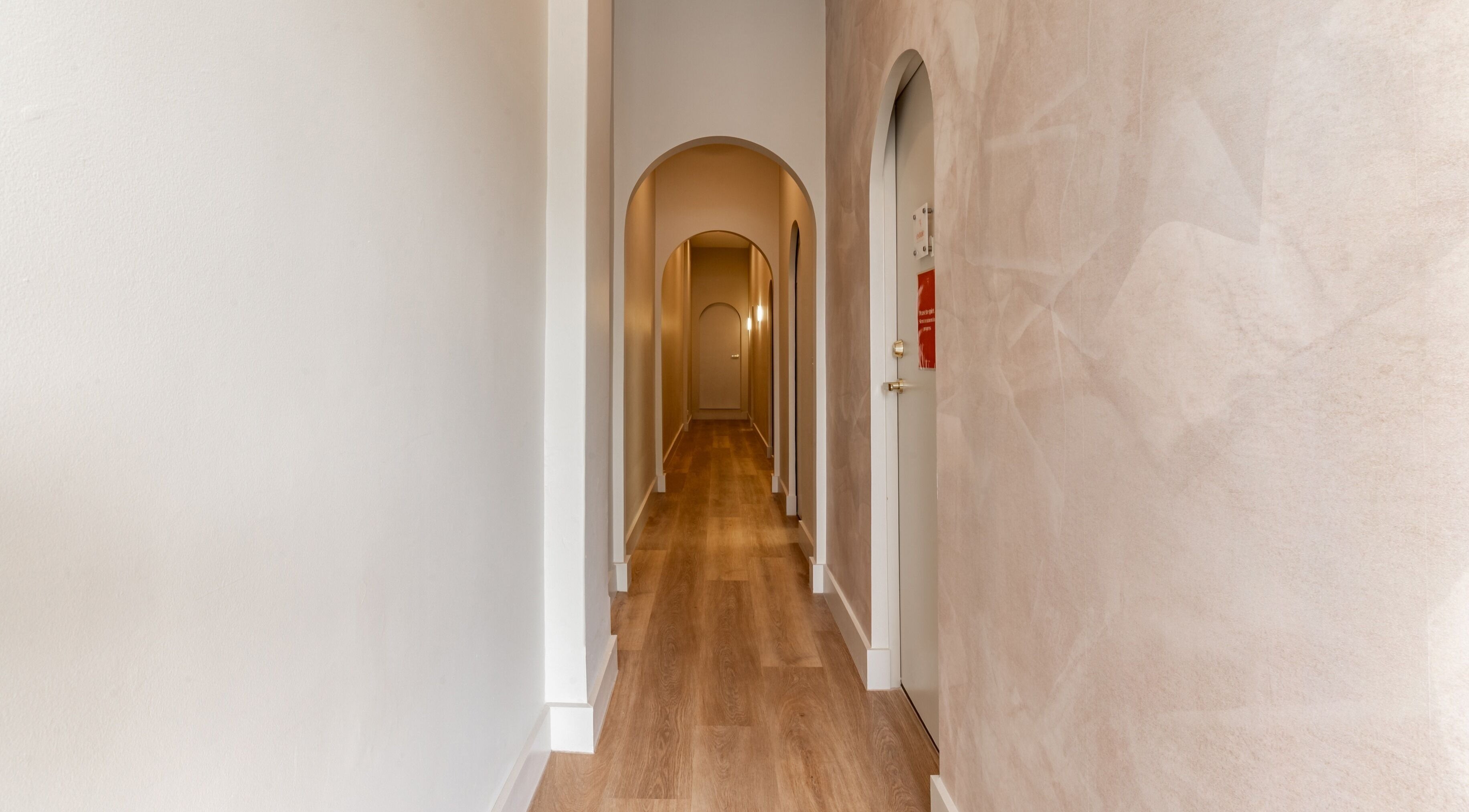 Serene hallway at Exhale Holistic Skin in Bentleigh East, Victoria, AU, featuring elegant arches and wood flooring.