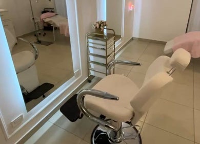 Interior moderno de Ana Laura Makeup Studio en Culiacán Rosales, Sinaloa, MX con sillas blancas y elegante espejo.