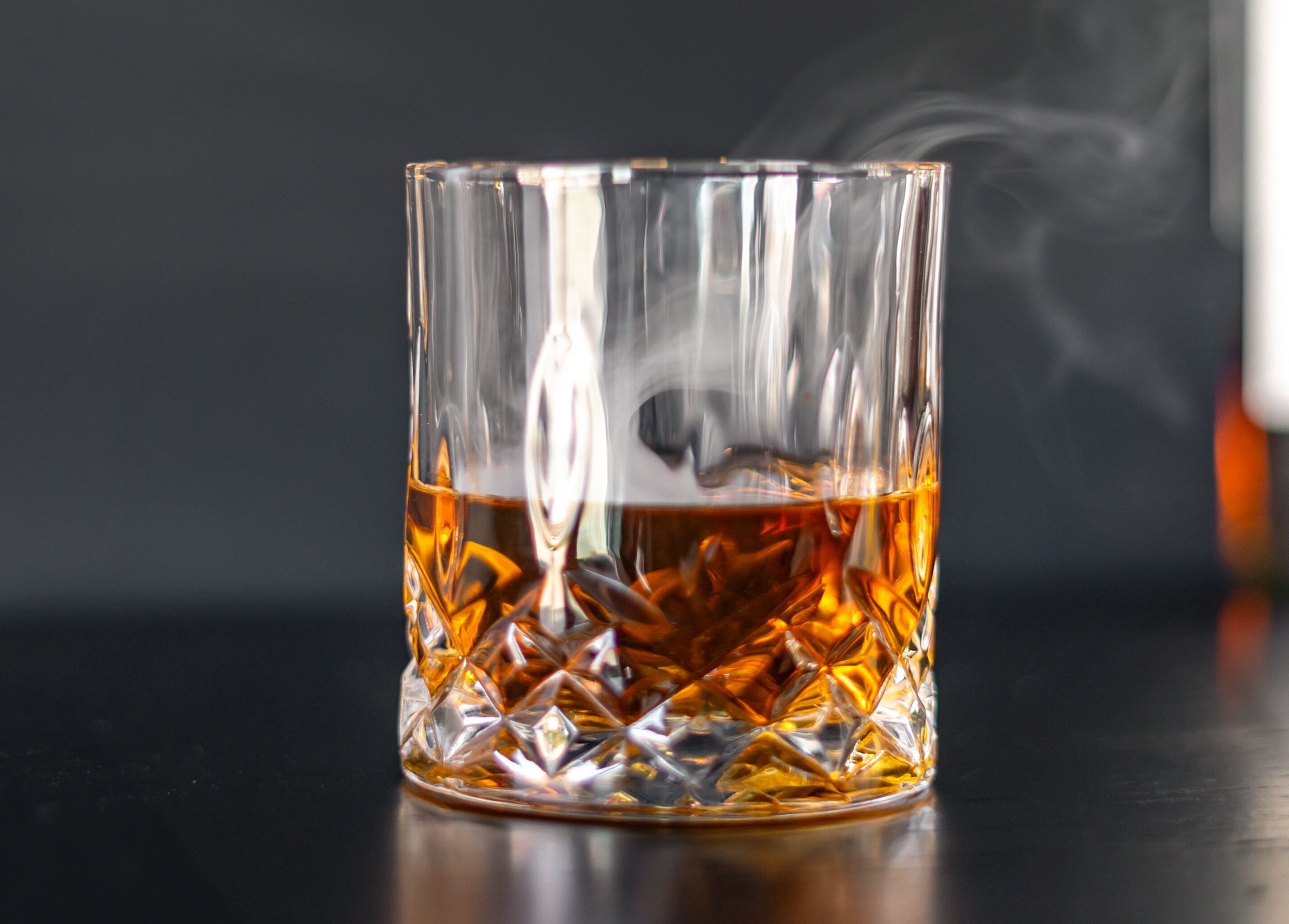 A glass of whiskey at The Belmont - A Barber Collective in Calgary, Alberta, CA, reflecting a cozy ambiance.