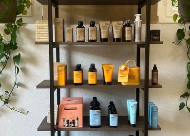 Shelves with beauty products at Belinda’s Hair Lounge & Beauty in Kilchberg, Zürich, CH, framed by vibrant plant vines.