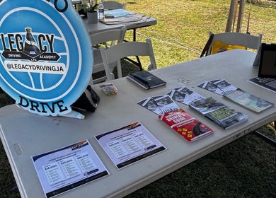 Legacy Driving Academy | Yallahs display table at Yallahs, St. Thomas Parish, JM with brochures and materials.