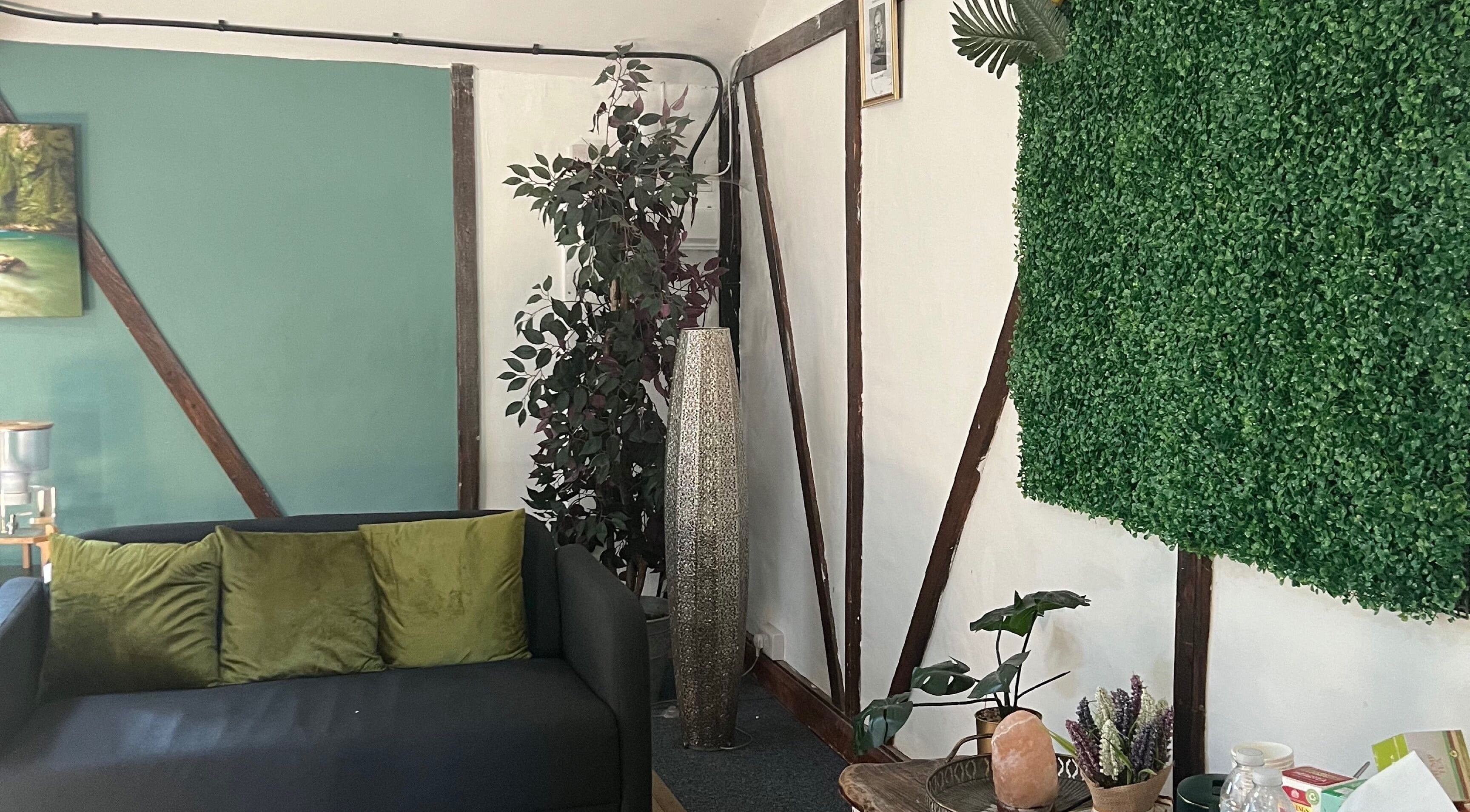 Cozy seating area in The Haven Room, Manchester, GB with green decor and plants, creating a tranquil ambiance.
