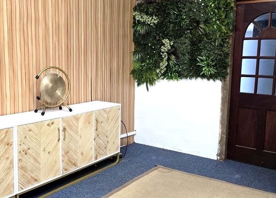 Stylish interior of The Unity Room, Carrington, England, GB with lush plant wall and wooden accents.