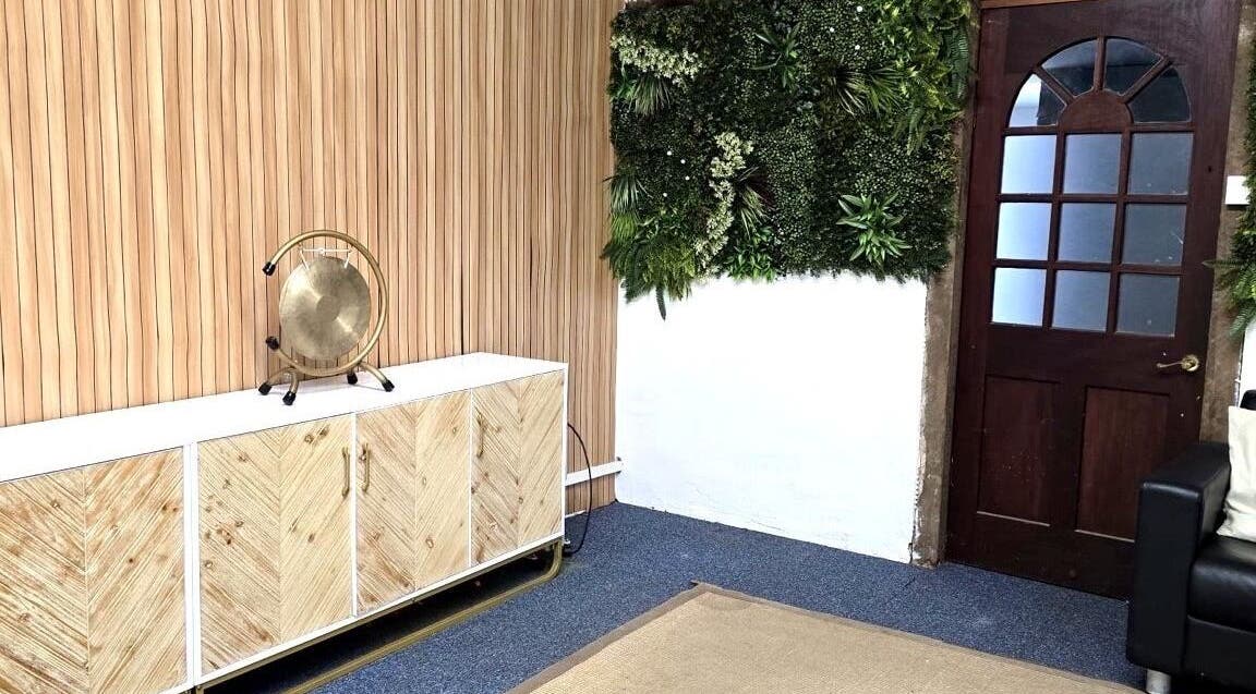 Stylish interior of The Unity Room, Carrington, England, GB with lush plant wall and wooden accents.