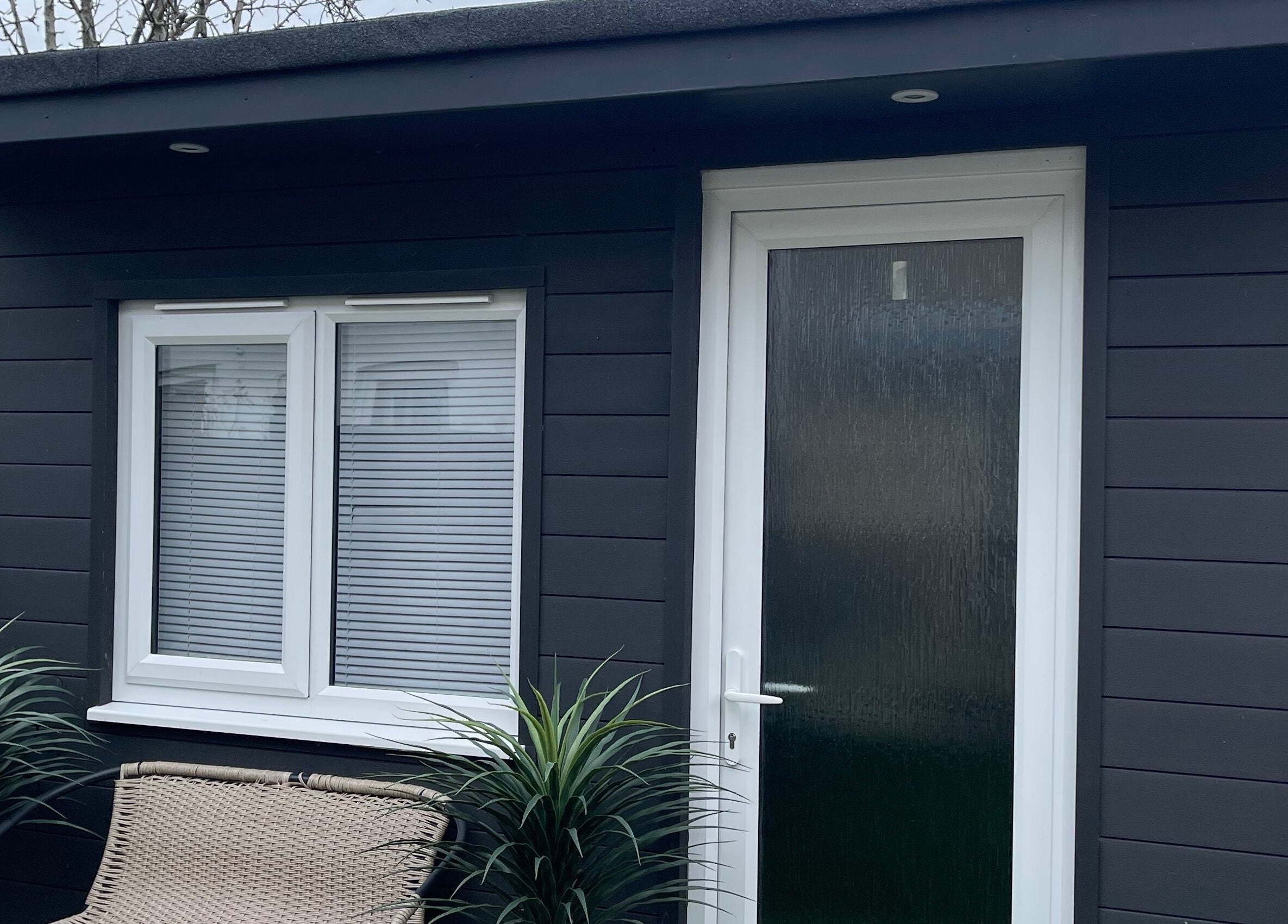 Sleek exterior of Taylor Fenton Cosmetics, Whitstable, England, GB, framed by lush greenery.