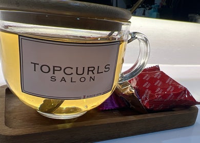 Warm tea in branded cup at Topcurls Salon, Singapore, SG, showcasing a welcoming and relaxing atmosphere.