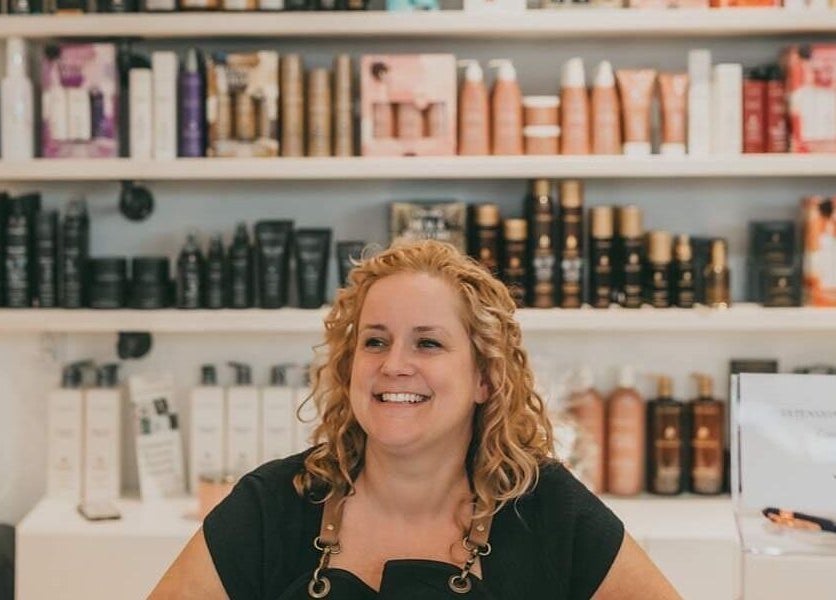 Professionnelle souriante à Institut 351, Saint-Eustache, Québec, CA devant produits beauté.