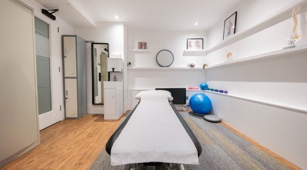 Modern therapy room at Physio Reform, London, England, GB, featuring a treatment bed and exercise equipment.