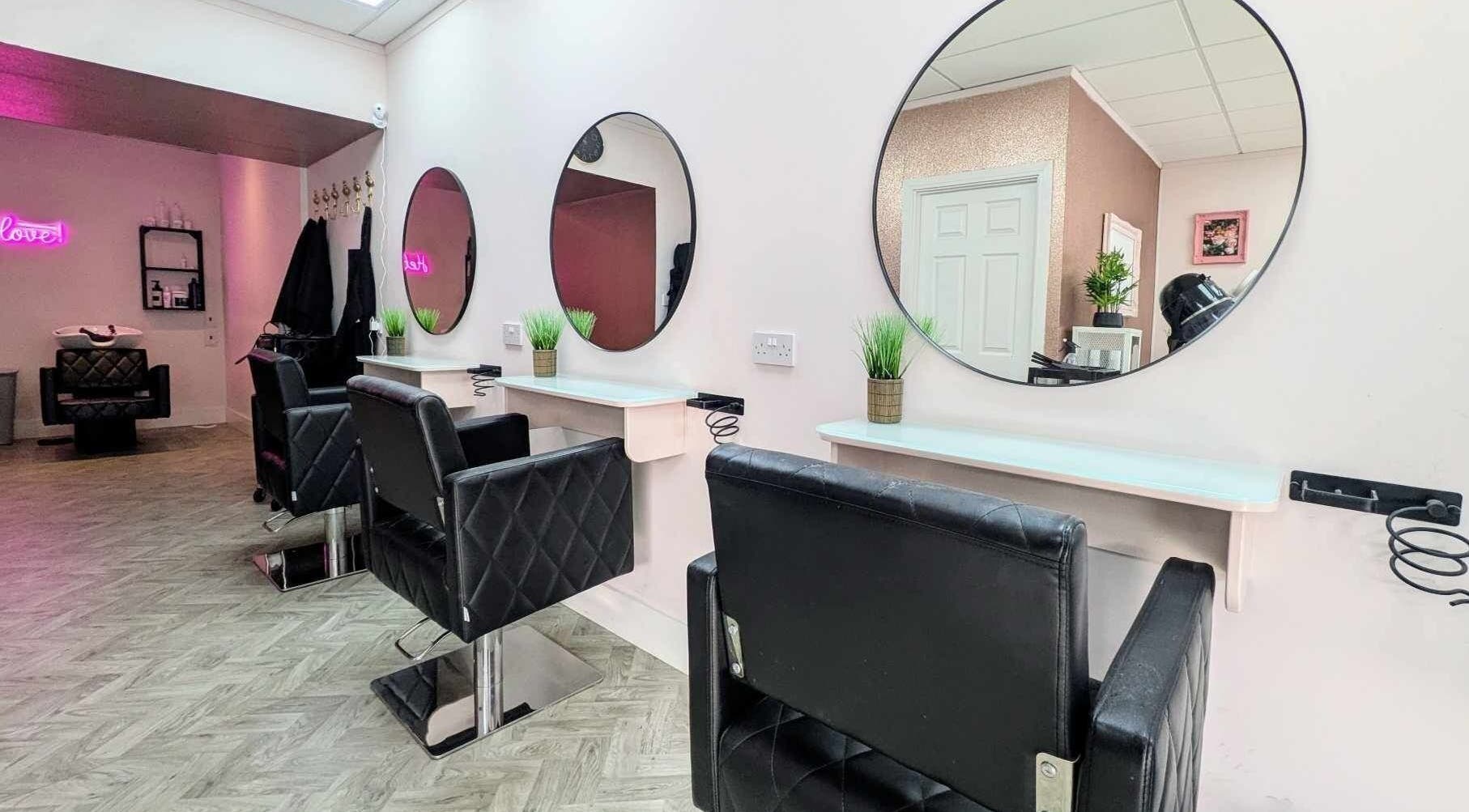 Modern salon interior at Poppys Hair and Beauty, Bristol, England, GB featuring stylish black chairs and round mirrors.