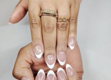 French tip manicure on a hand with gold rings at Studio 59, Rumney, Wales, GB.