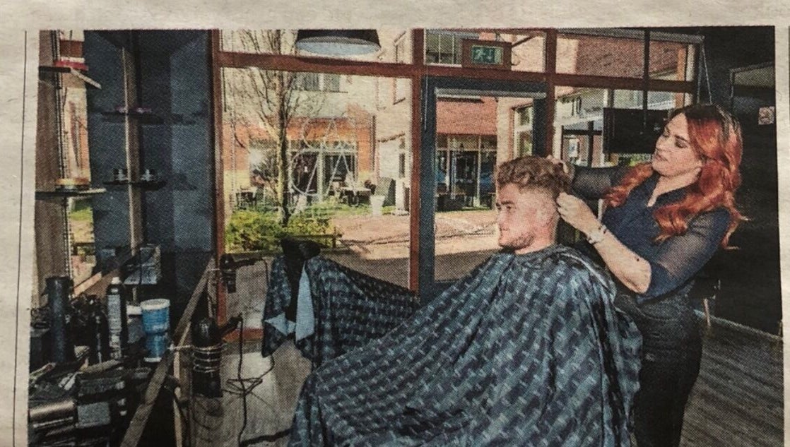 Kapper aan het werk bij V Artistry in Ravels, Vlaanderen, BE, met moderne inrichting en natuurlijk licht.