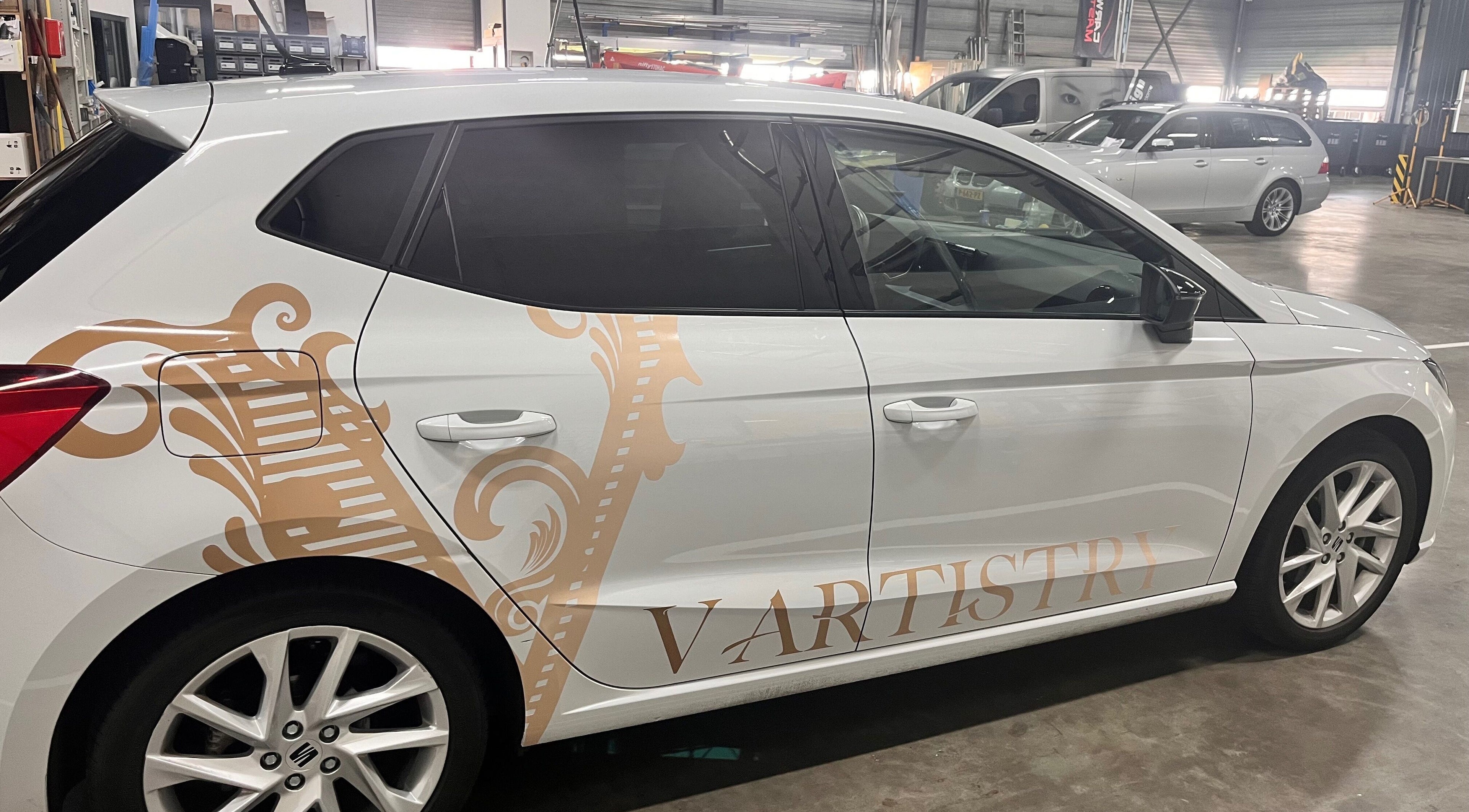 Beschilderde auto met V Artistry logo in werkplaats, Ravels, Vlaanderen, BE.