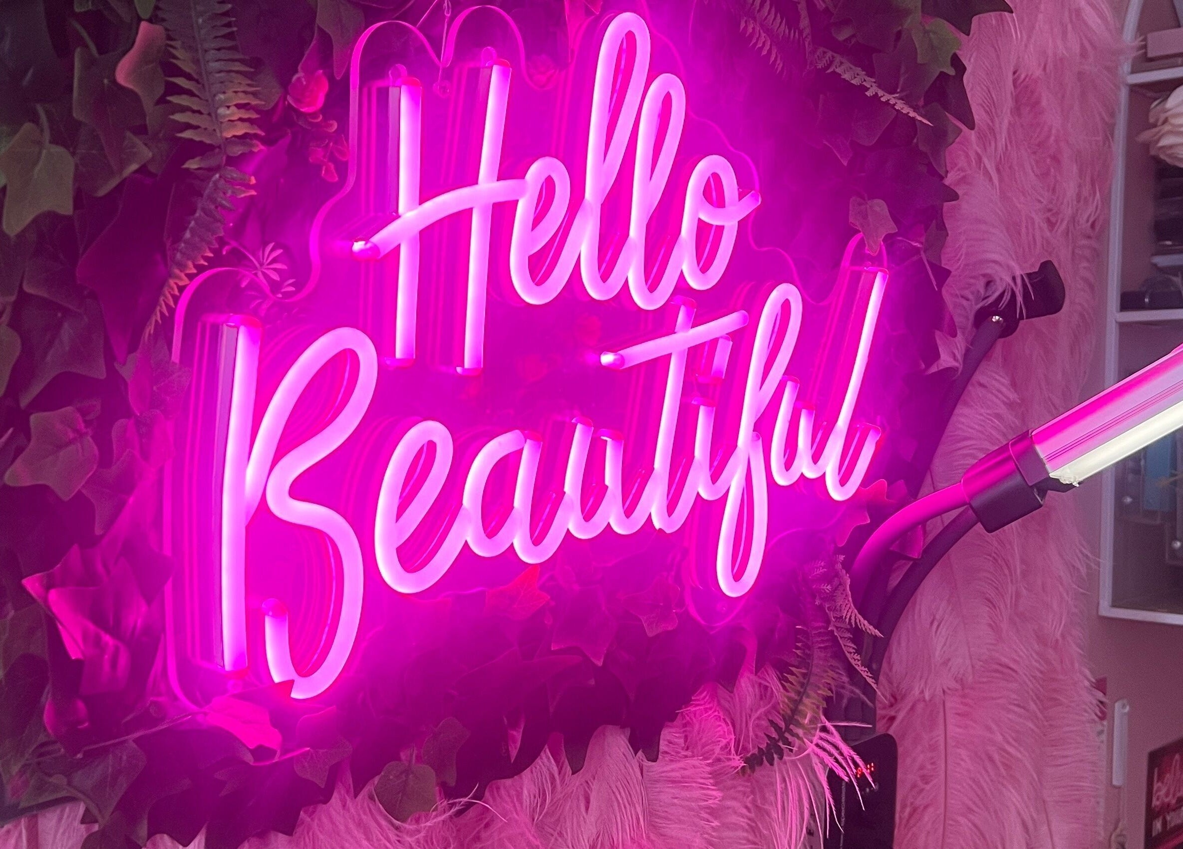 SlayedbySophie in Folkestone, England features a vibrant pink neon sign with 'Hello Beautiful' greeting.