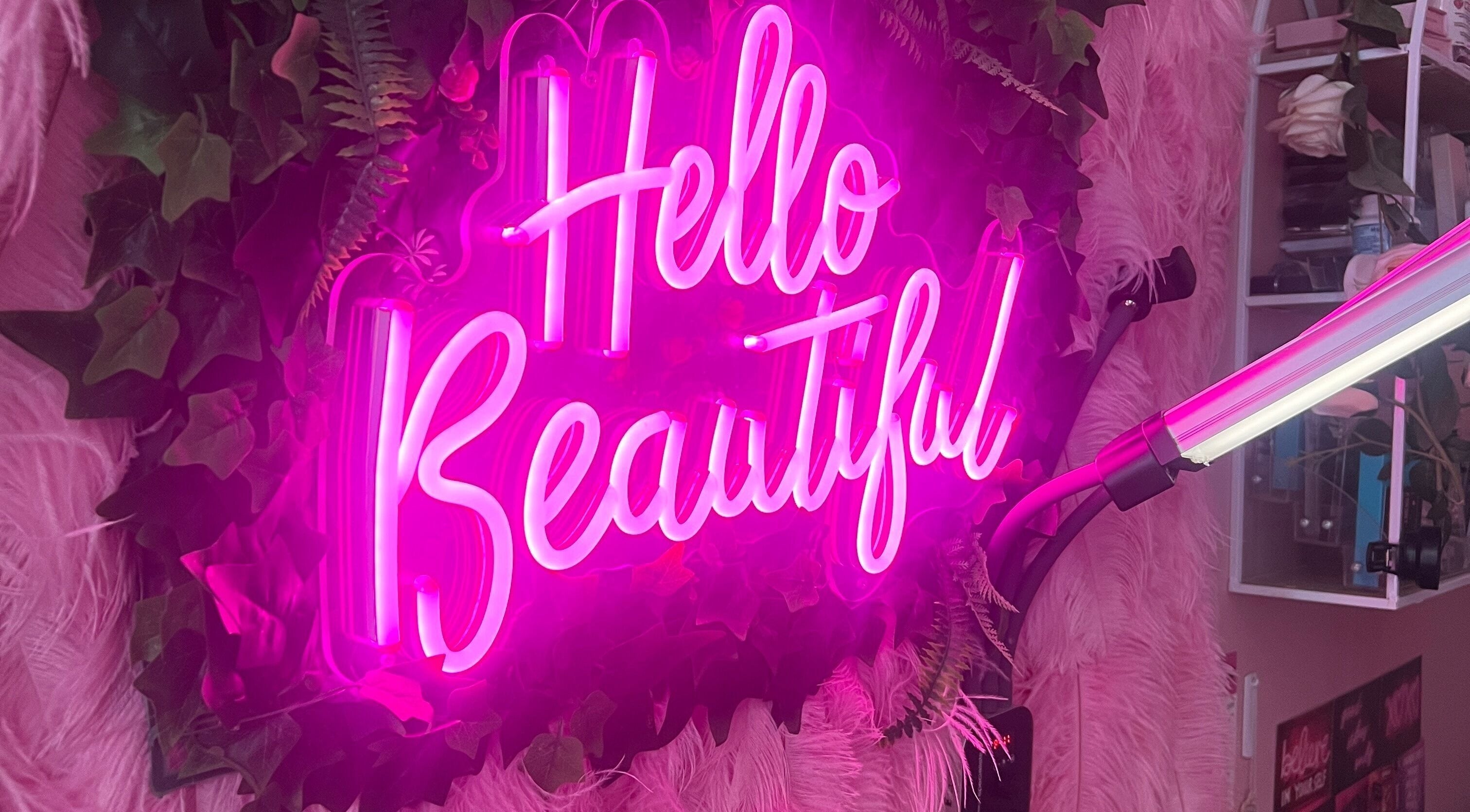 SlayedbySophie in Folkestone, England features a vibrant pink neon sign with 'Hello Beautiful' greeting.