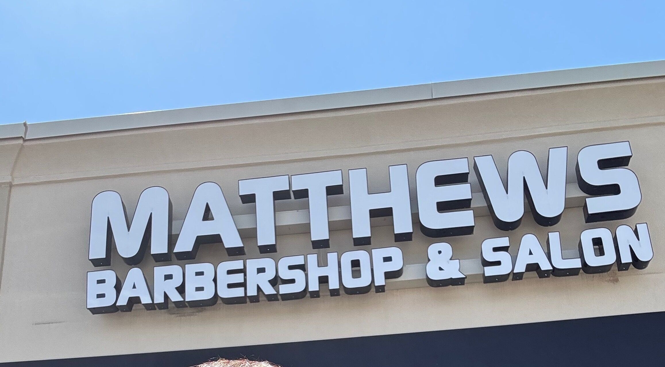Signage of Matthews Barber Shop and Salon, Matthews, North Carolina, US, on a sunny day.