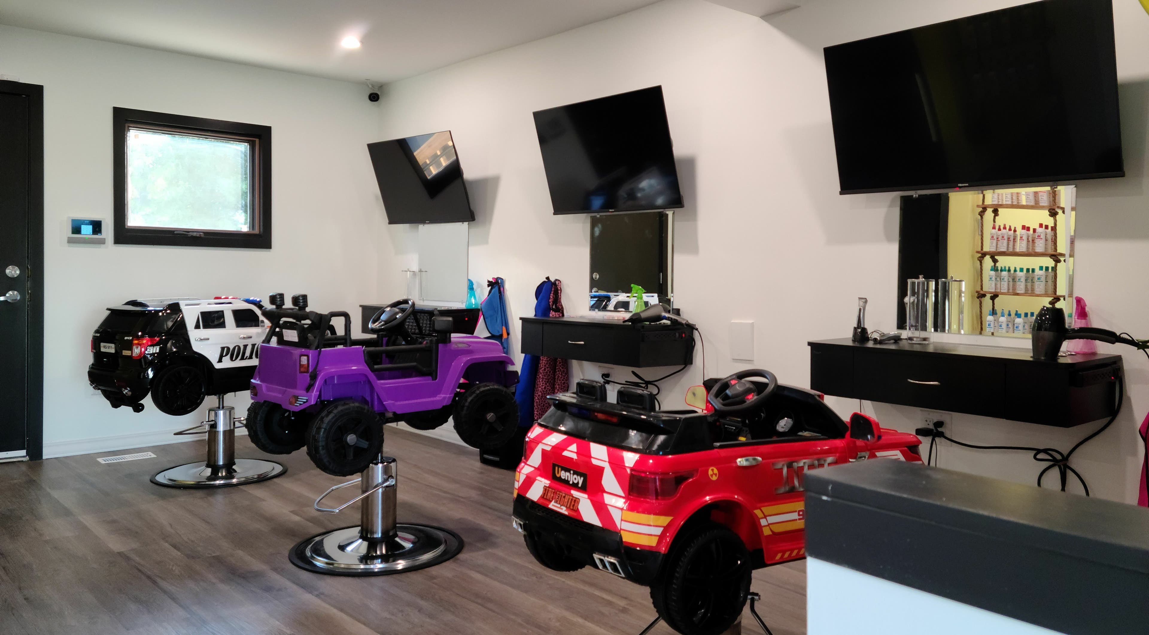 Fun styling chairs at Mane Tamers Salon For Kids, Winnipeg, Manitoba, CA, with toy vehicles for children.