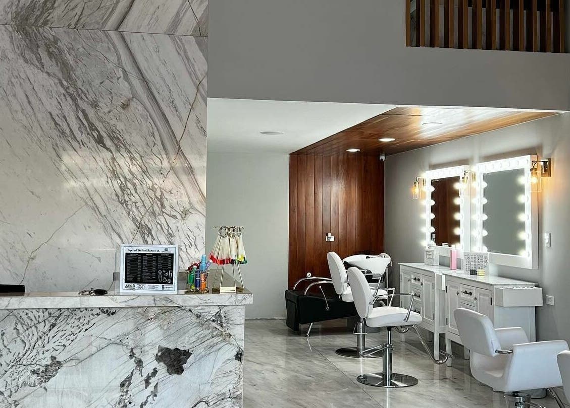 Interior elegante de Eztravaganzza Nailroom Plus en Chihuahua, MX, con sillas blancas y decoración en mármol.