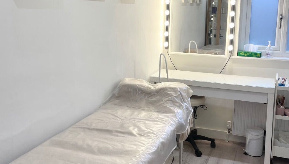 Treatment room at Madison Aesthetics, Berkhamsted, England, GB, featuring a bed and vanity with lit mirror.
