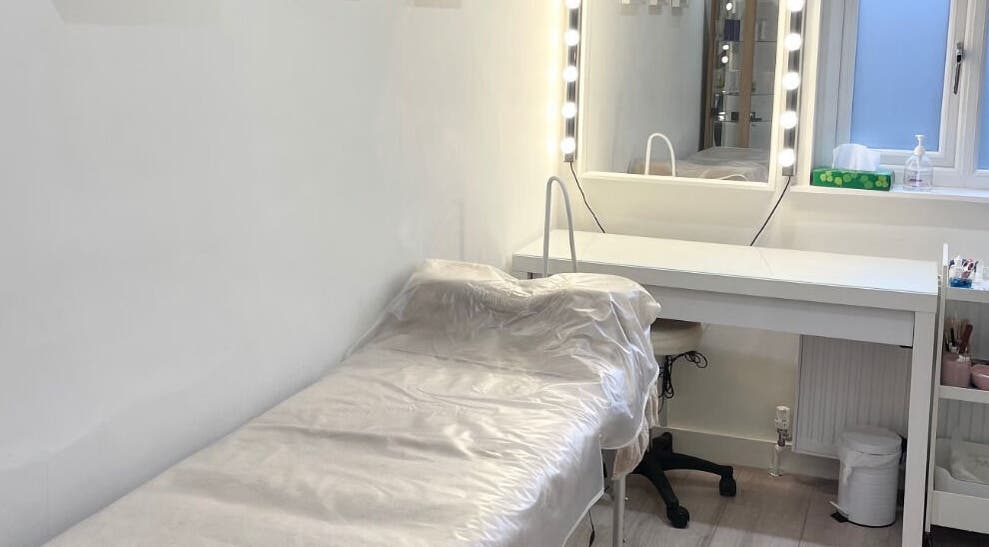 Treatment room at Madison Aesthetics, Berkhamsted, England, GB, featuring a bed and vanity with lit mirror.