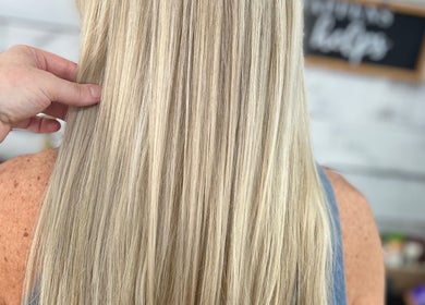 Stylist refining smooth, long blonde hair at Luna Jade Salon Independant Stylists, Athens, Alabama, US.