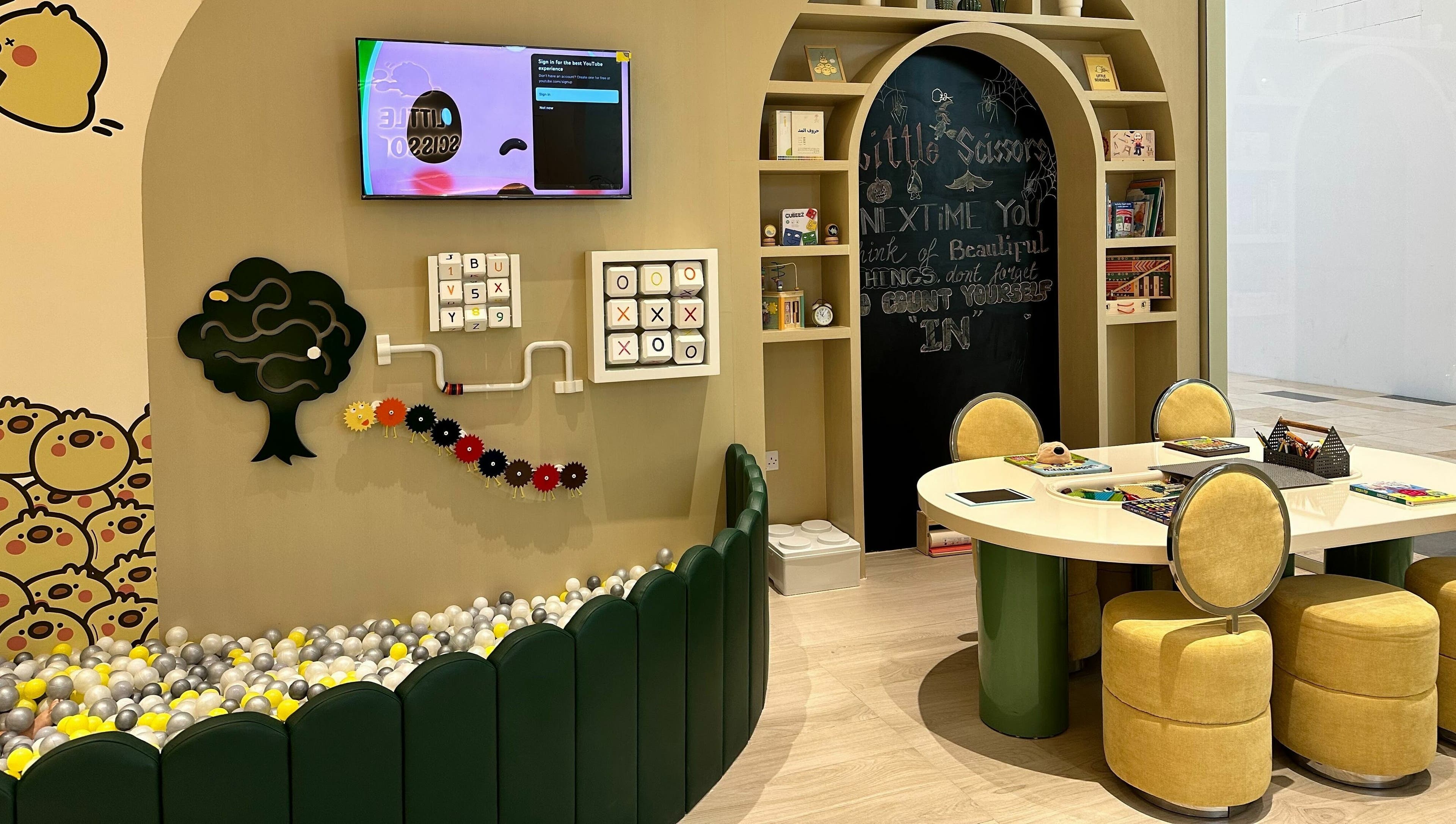 Play area at Little Scissors Kids Salon in Abu Dhabi, AE, featuring games and a cozy seating for children.