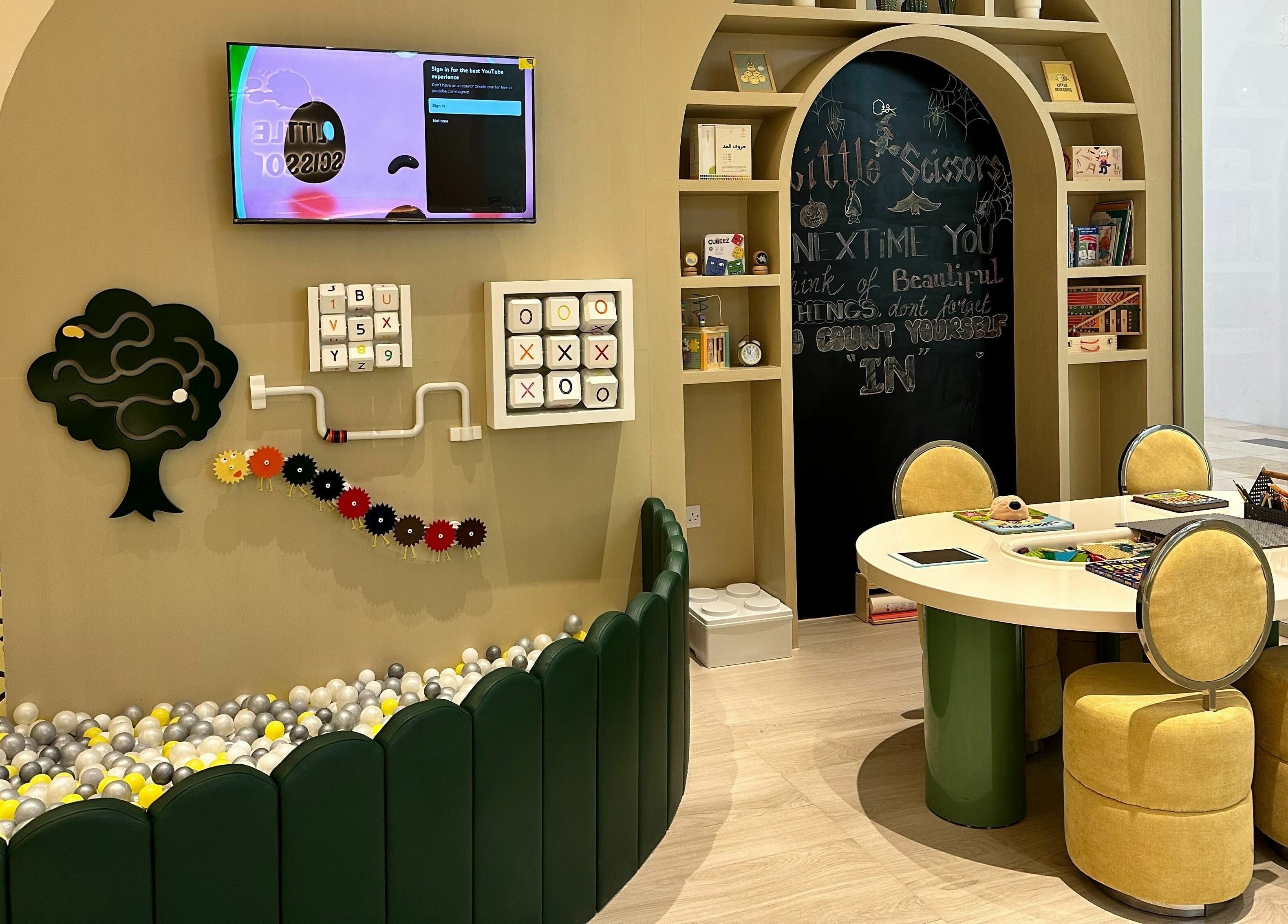 Play area at Little Scissors Kids Salon in Abu Dhabi, AE, featuring games and a cozy seating for children.