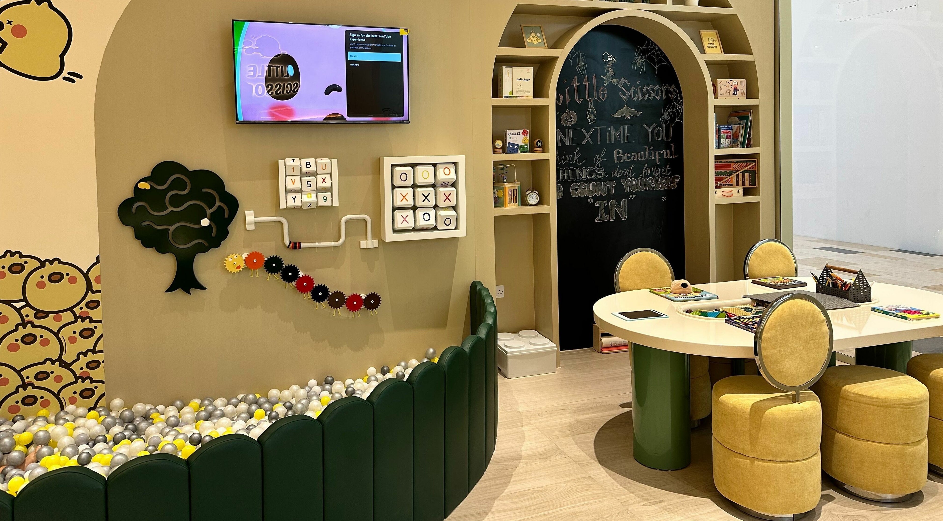 Play area at Little Scissors Kids Salon in Abu Dhabi, AE, featuring games and a cozy seating for children.