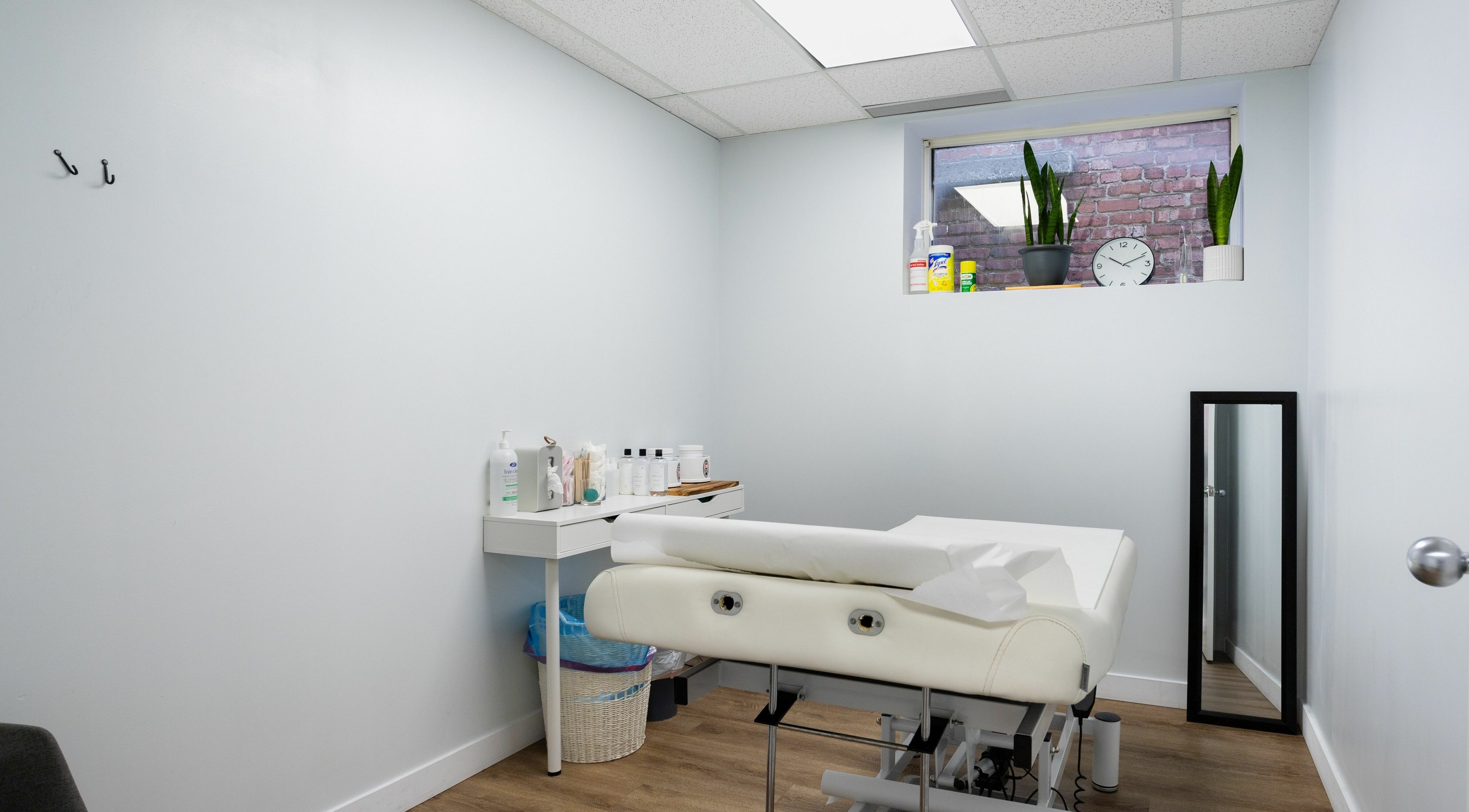 Calm treatment room at Lovely Sugaring, Toronto, Ontario, CA featuring a bed, mirror, and plants.