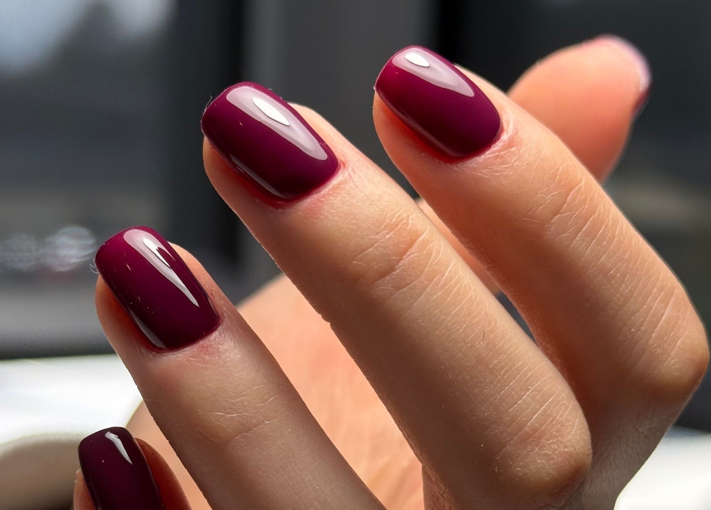 Close-up of maroon manicured nails at La Petite Onglerie & Co., Mascouche, Québec, CA, showcasing elegant nail art.