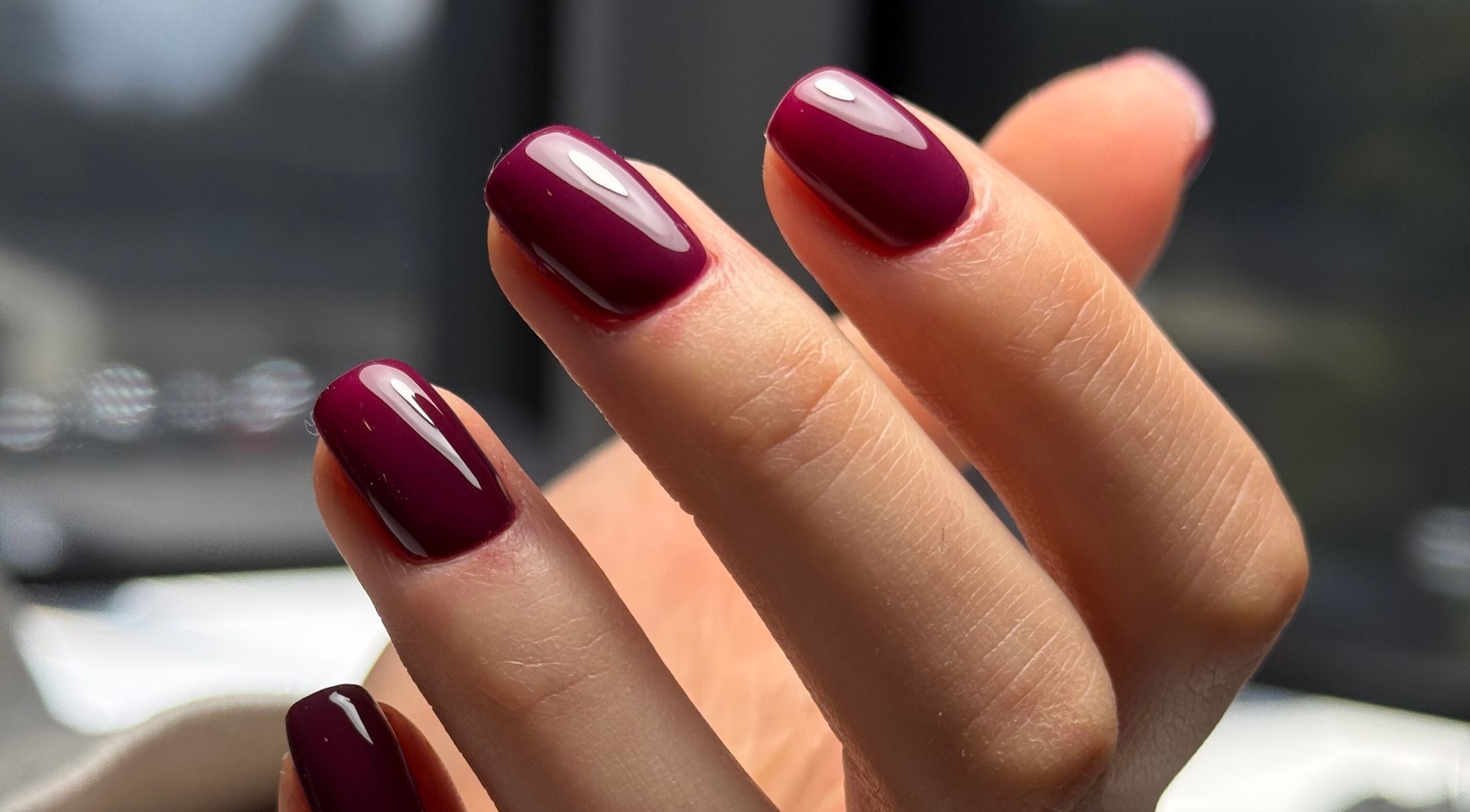Close-up of maroon manicured nails at La Petite Onglerie & Co., Mascouche, Québec, CA, showcasing elegant nail art.