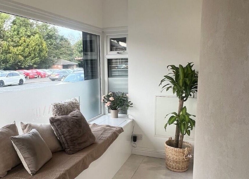 Cozy waiting area at AURA THE CLINIC, Newcastle upon Tyne, England, with soft pillows and plants.