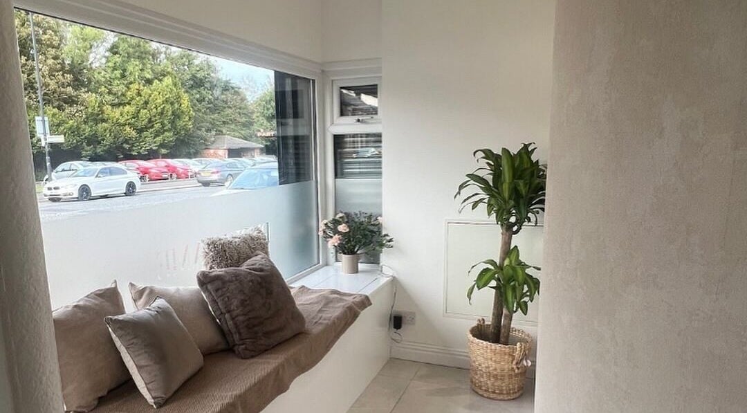Cozy waiting area at AURA THE CLINIC, Newcastle upon Tyne, England, with soft pillows and plants.