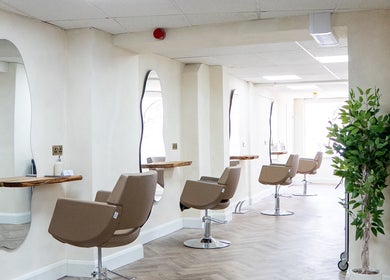 Modern salon interior at Jennifer Holmes Hair and Beauty Ltd, Masham, England, GB, featuring sleek chairs and mirrors.