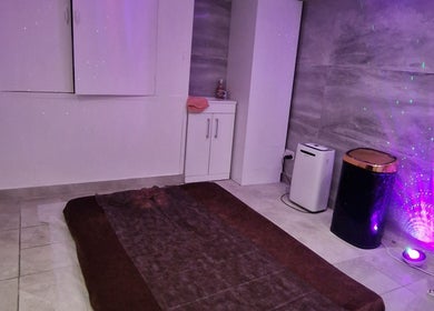 Dimly lit relaxation room at La Baba, London, England, GB with soothing purple lights and a cozy mat.