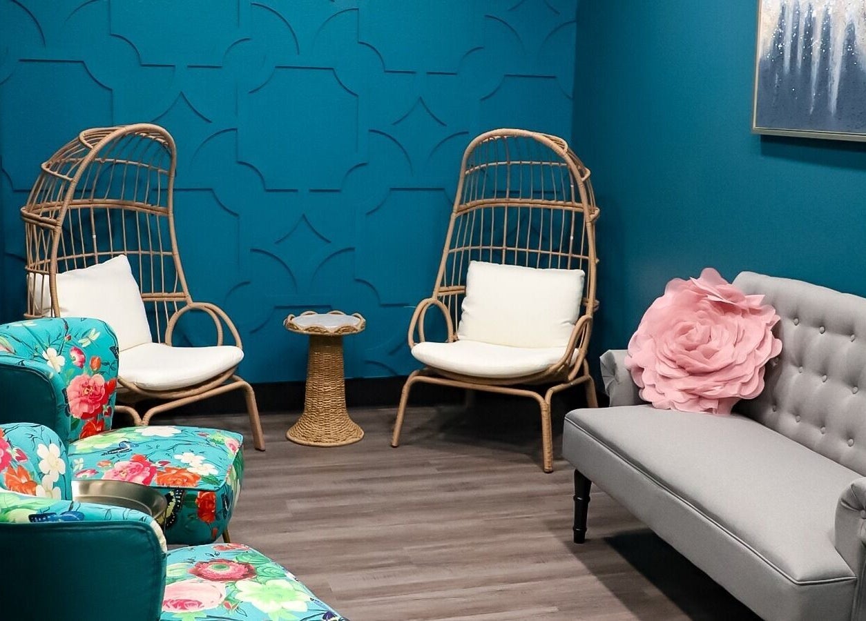 Serene lounge at Spa Haven Suites, Henderson, Nevada, US, featuring cozy wicker chairs and vibrant floral decor.