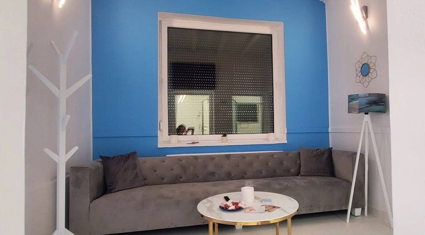 Salon modern la Dermatique, Timișoara, Județul Timiș, RO cu canapea gri și pereți albaștri.